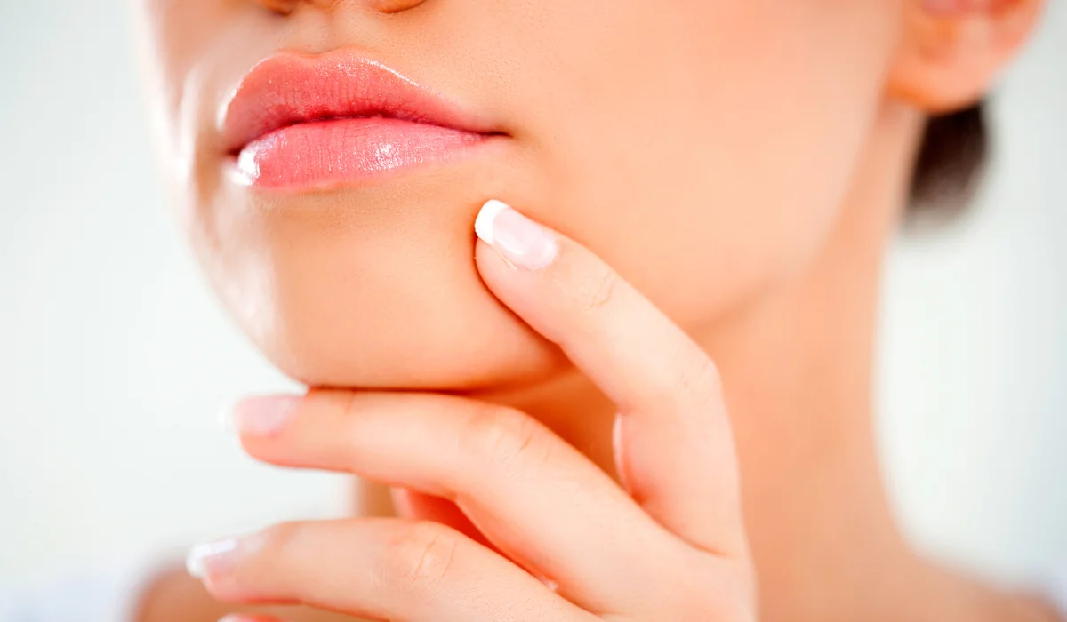 Mulher passando a mão no queixo em um processo de recuperação da mentoplastia