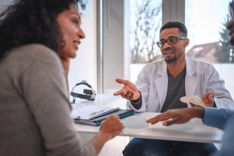 Cirurgião plástico conversando com paciente sobre lifting de mamas, explicando a diferença entre a cirurgia com e sem prótese