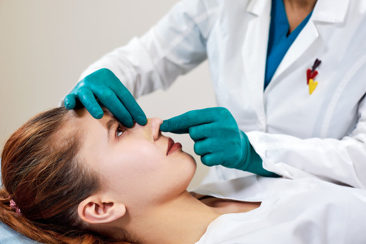 Médica examinando o nariz de uma paciente após procedimento de rinoplastia funcional