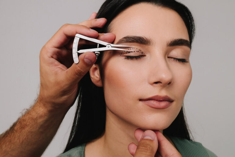 Avaliação prévia à cirurgia de blefaroplastia, com marcações nas pálpebras e instrumento de medição sendo usado por profissional de saúde.