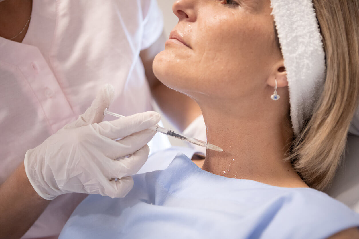 Mulher recebendo aplicação estética no pescoço para tratamento de rugas e rejuvenescimento da pele na região