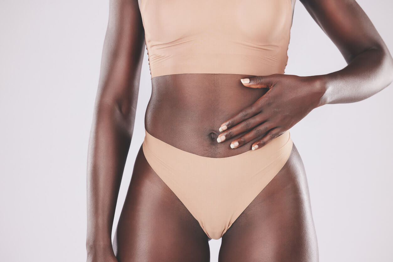 Mulher com a mão sobre o abdômen exibe resultado definido da lipo na barriga, procedimento estético que remove gordura localizada e realça o contorno corporal.