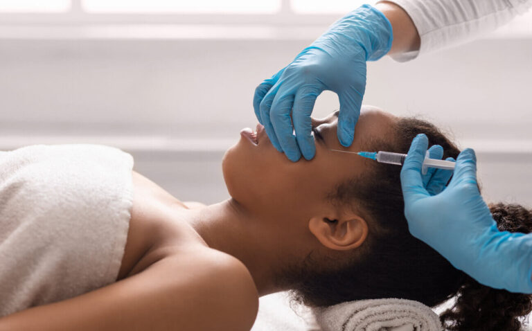 Profissional aplica injeção no rosto de uma mulher durante sessão de procedimentos estéticos minimamente invasivos, voltados para rejuvenescimento e harmonização facial sem cirurgia.