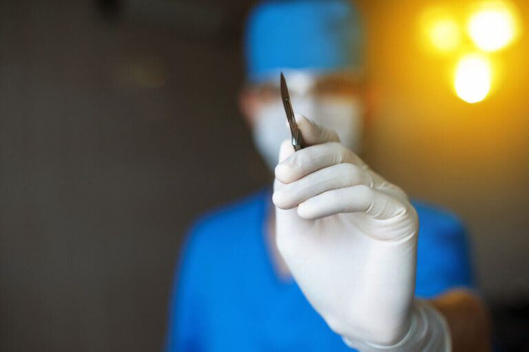 Cirurgião segurando um bisturi durante preparação para procedimento, representando a precisão necessária nas técnicas avançadas como o deep plane.