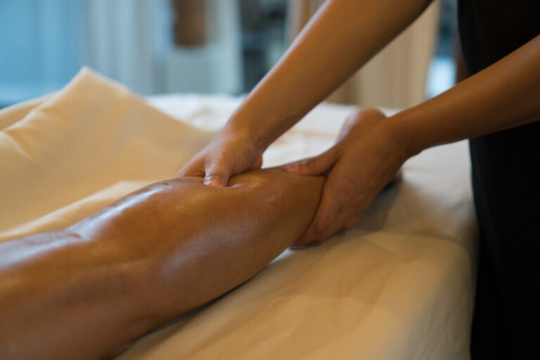 Profissional realizando massagem terapêutica na perna de uma paciente, prática muitas vezes vinculada aos mitos do lipedema sobre tratamento e alívio dos sintomas.