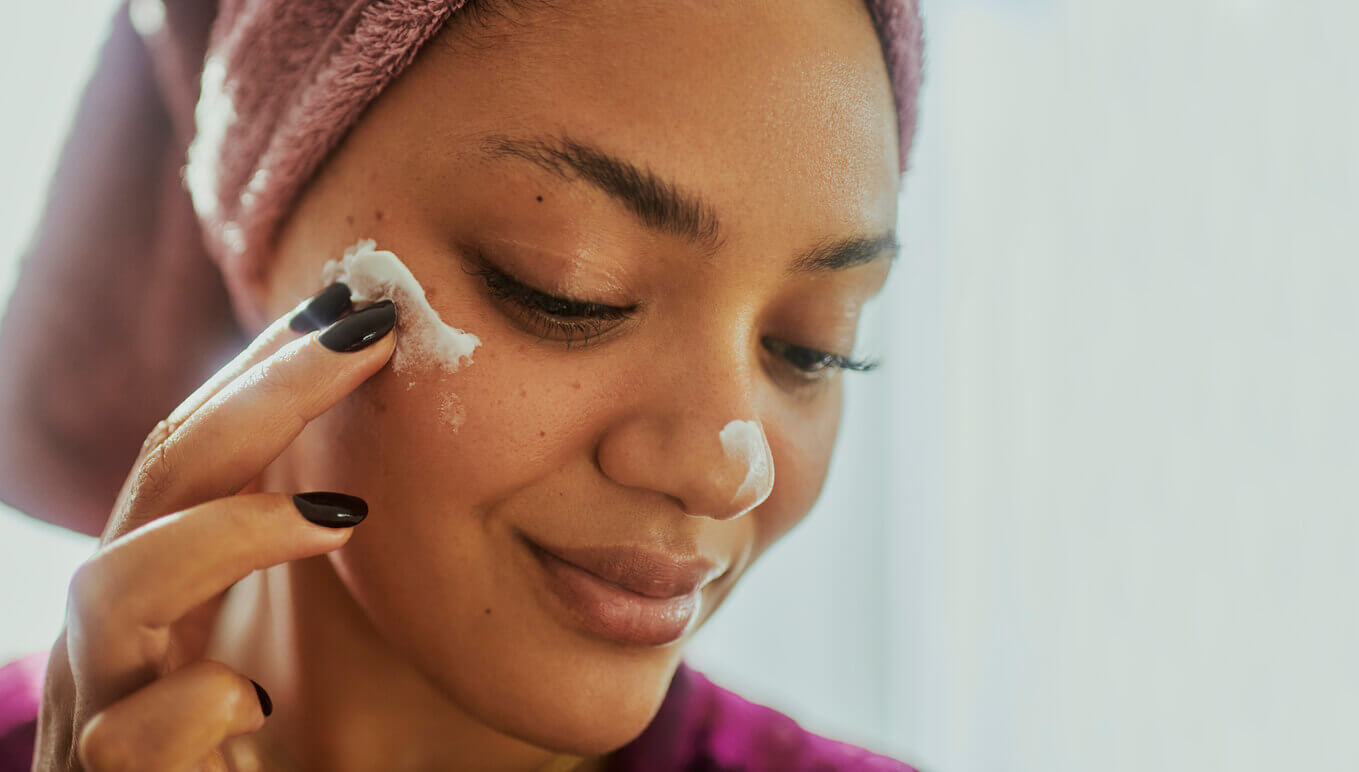 mulher aplicando creme hidratante no rosto após rotina de cuidados com a pele para potencializar o rejuvenescimento facial