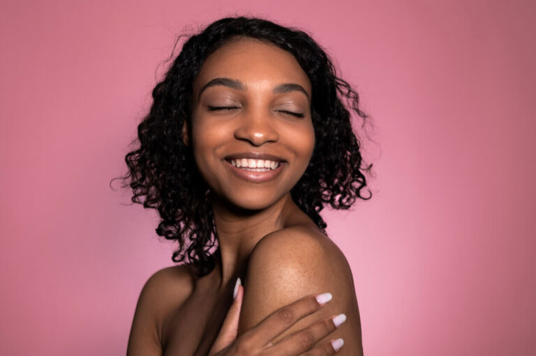 Mulher com pele uniforme e luminosa sorrindo, representando os resultados do resurfacing na renovação da textura e no estímulo de colágeno da pele.