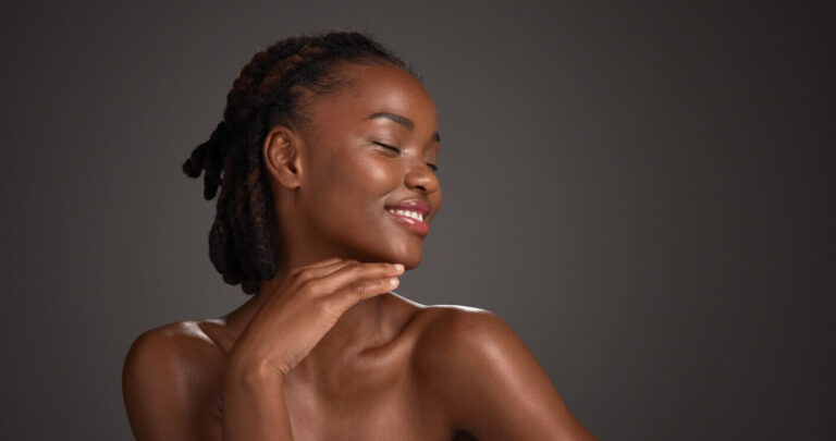 Mulher sorrindo com a mão apoiada no queixo, representando os cuidados após preenchimento facial e a busca por um resultado natural e harmonioso