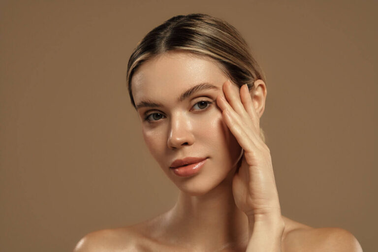 Mulher com pele firme e aspecto rejuvenescido tocando o rosto, representando o resultado do lifting deep plane facial e sua durabilidade ao longo do tempo.