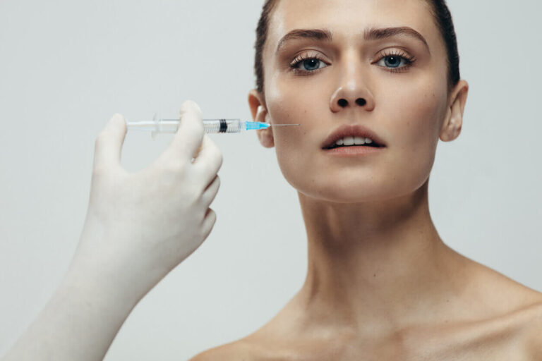 Aplicação de preenchimento facial com seringa na região da bochecha durante procedimento estético para harmonização do rosto