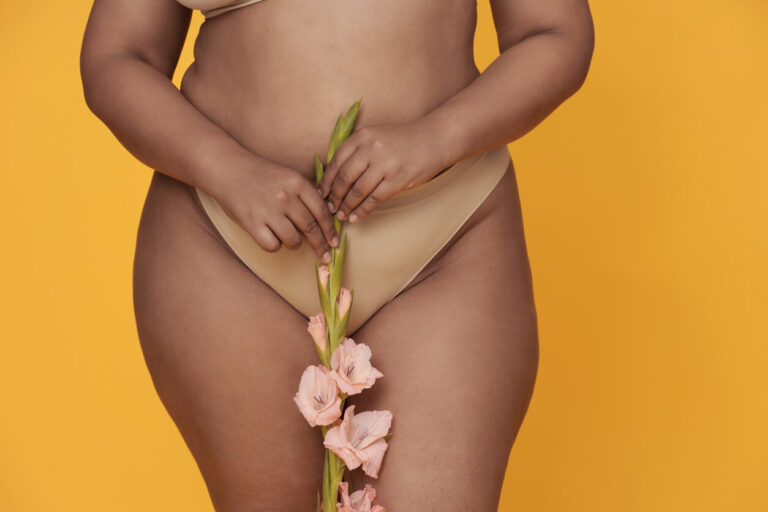 Pessoa segurando uma flor sobre a região íntima, representando cuidados estéticos e avaliação para ninfoplastia.