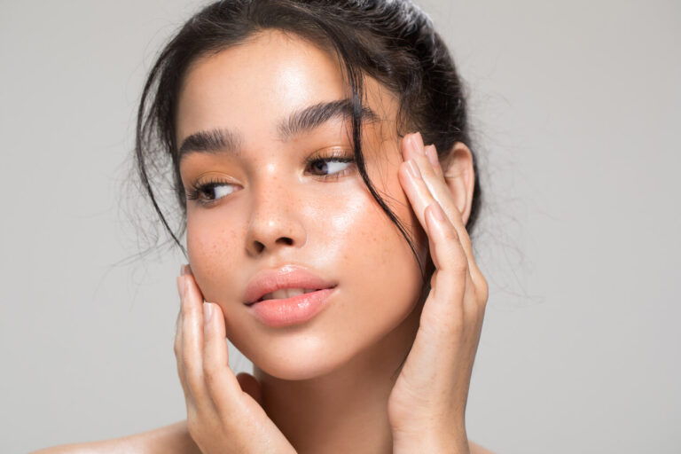 Mulher com pele iluminada em close no rosto, representando cuidados faciais e procedimentos estéticos em alta.