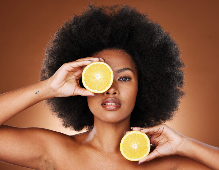Mulher segurando laranjas junto ao rosto para representar a alimentação durante a recuperação do lifting facial