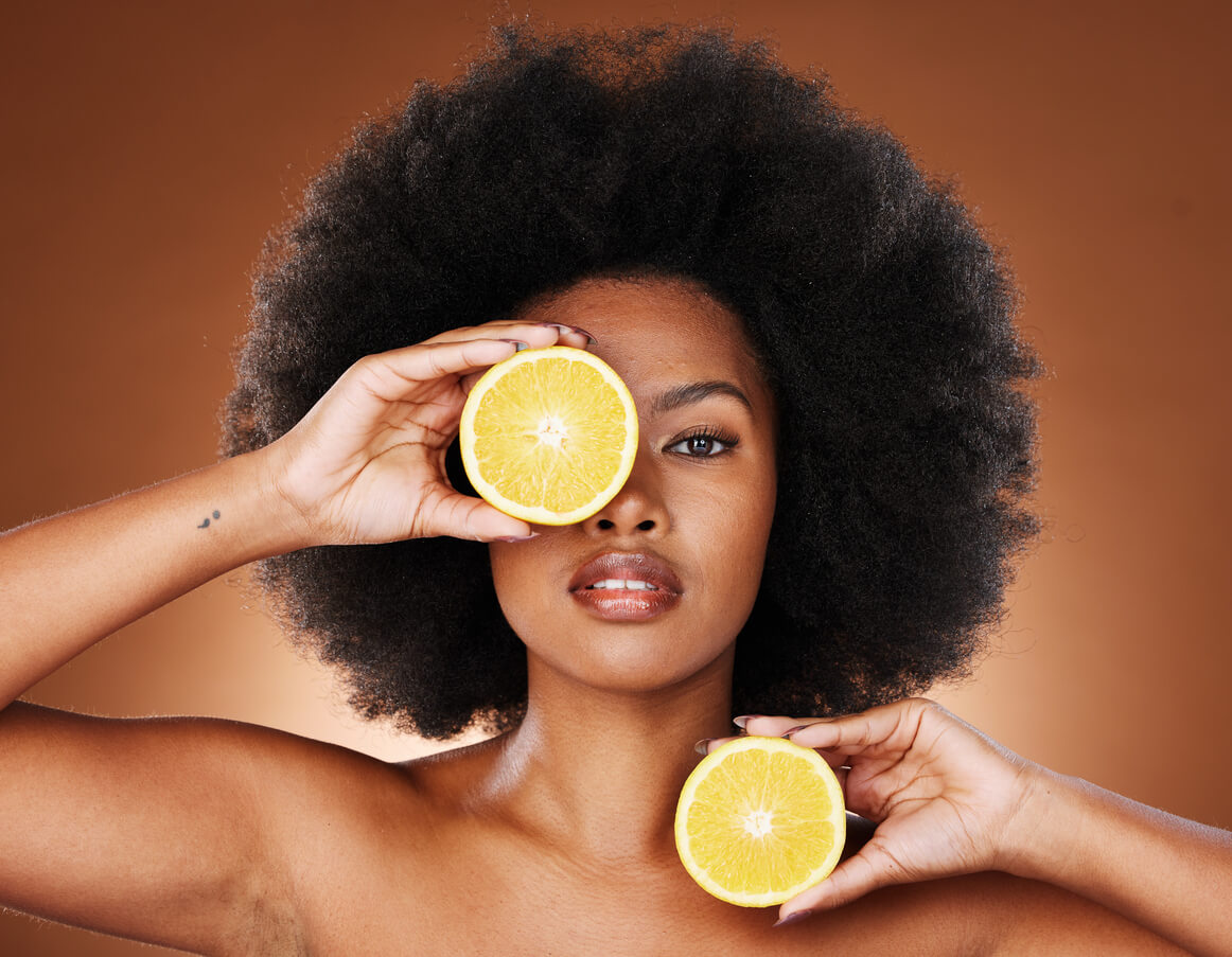 Mulher segurando laranjas junto ao rosto para representar a alimentação durante a recuperação do lifting facial