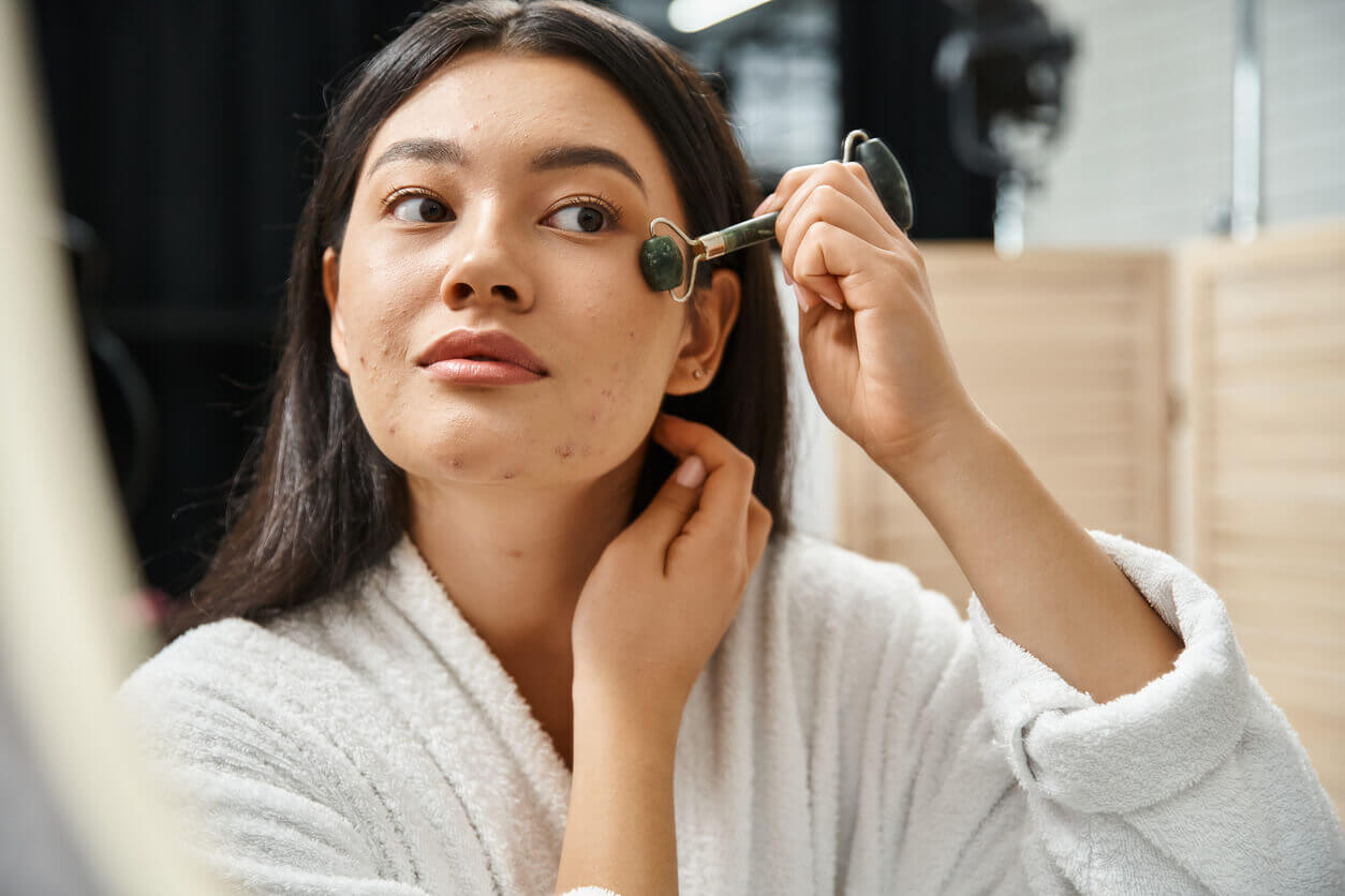 Mulher usando um massageador facial no rosto, com cicatrizes deprimidas de acne.