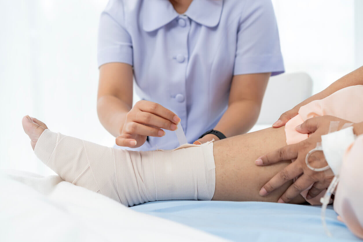 Paciente recebendo cuidados no pós-operatório da cirurgia para lipedema, com curativo e faixa na perna.