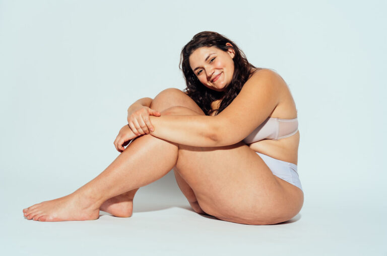 Mulher sentada com as pernas dobradas, ilustrando as regiões do corpo que podem ser tratadas pela cirurgia de lipedema.