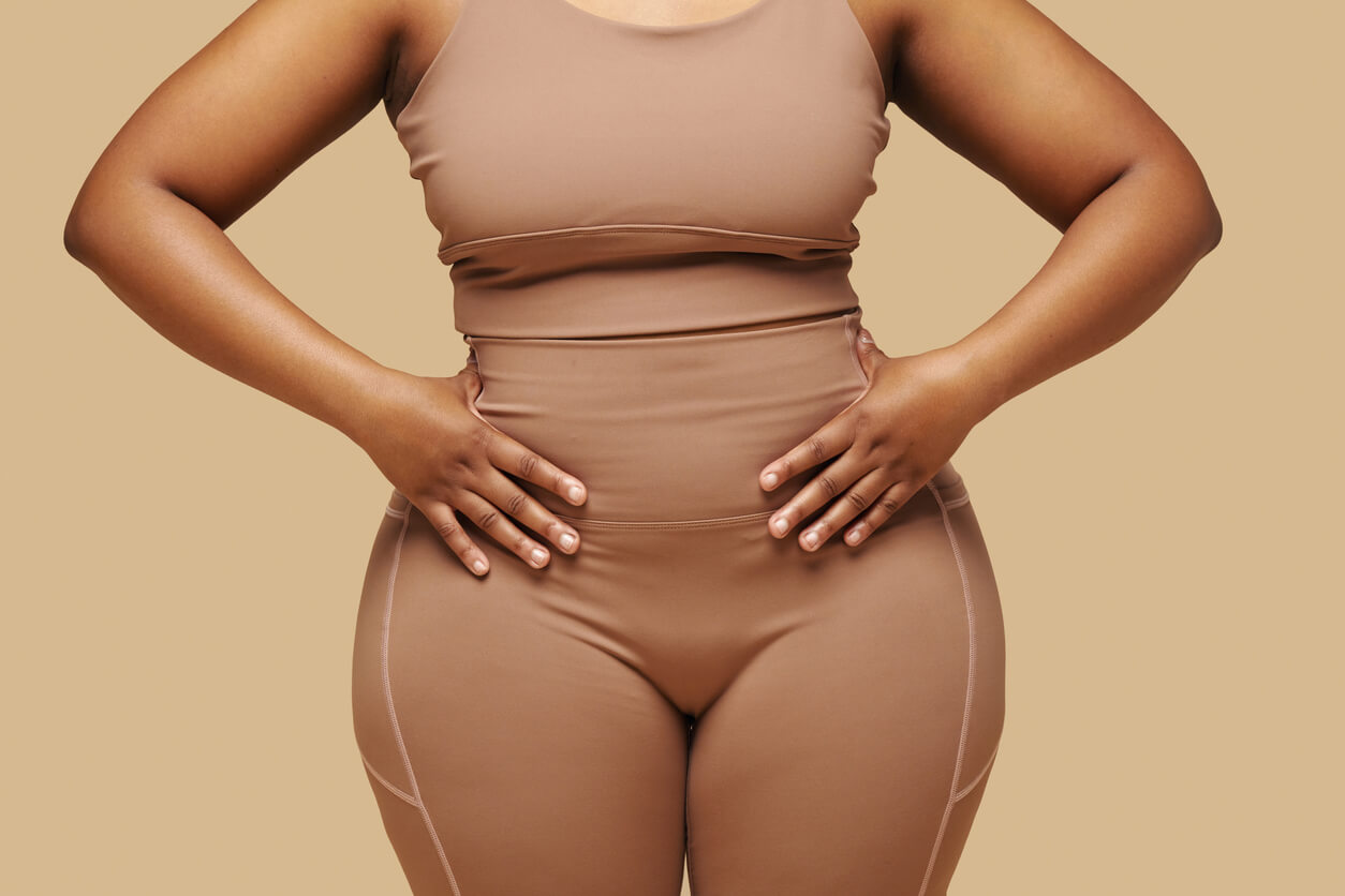 Mulher com as mãos na cintura, representando os cuidados com o corpo e a prevenção da obesidade após o emagrecimento.