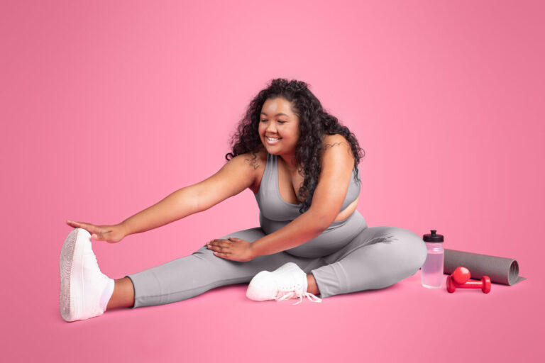 Mulher sentada realizando alongamento das pernas, ilustrando a importância da mobilidade e da atividade física diante dos sintomas de lipedema.