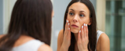 mulher no espelho vendo sinais de fadiga facial.