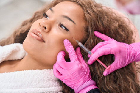 Profissional realizando aplicações de botox no rosto de uma mulher em ambiente clínico, com foco em suavização de linhas de expressão.