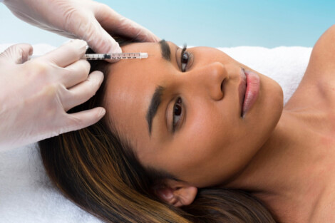 Mulher durante aplicação de Botox na testa com seringa, procedimento estético utilizado para suavizar linhas de expressão e rugas faciais.
