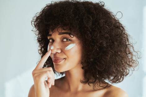 Mulher aplicando protetor solar no rosto, cuidado essencial entre os cuidados pós peeling facial para evitar manchas e irritações.