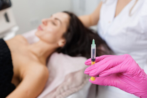 Profissional de saúde segura seringa próxima a paciente em clínica estética, ilustrando o tema da anestesia no Deep Plane Facelift.