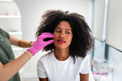 Profissional avalia a pele do rosto de uma mulher antes do tratamento de dermoabrasão