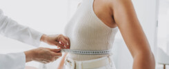 Mulher sendo medida com fita métrica na cintura durante consulta médica, simbolizando o acompanhamento de peso após cirurgia bariátrica. Mulher querendo estabilzar o peso.