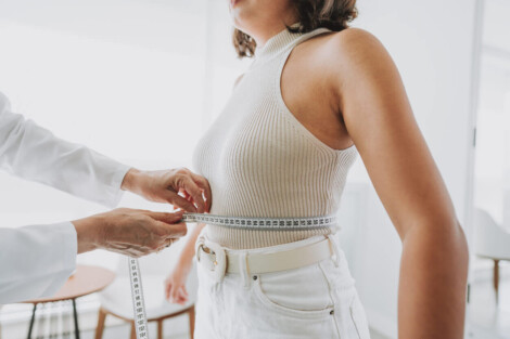 Mulher sendo medida com fita métrica na cintura durante consulta médica, simbolizando o acompanhamento de peso após cirurgia bariátrica. Mulher querendo estabilzar o peso.