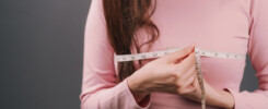Mulher medindo o busto com fita métrica, ilustrando o interesse pelos benefícios da mamoplastia redutora para estética e saúde