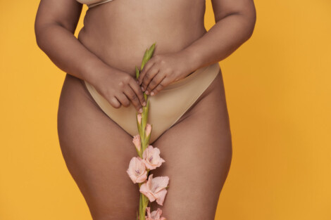 Pessoa segurando uma flor sobre a região íntima, representando cuidados estéticos e avaliação para ninfoplastia.