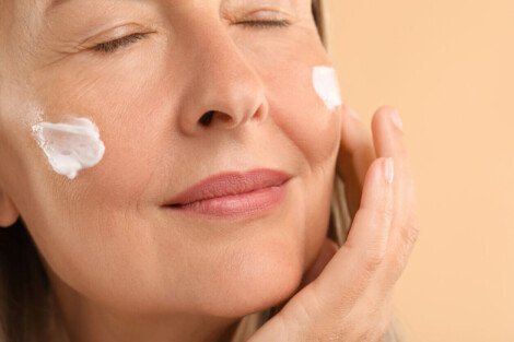 Mulher madura aplicando creme facial para cuidar da perda de colágeno no rosto durante a menopausa