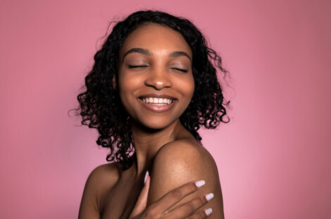 Mulher com pele uniforme e luminosa sorrindo, representando os resultados do resurfacing na renovação da textura e no estímulo de colágeno da pele.