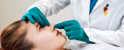Médica examinando o nariz de uma paciente após procedimento de rinoplastia funcional