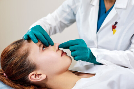 Médica examinando o nariz de uma paciente após procedimento de rinoplastia funcional
